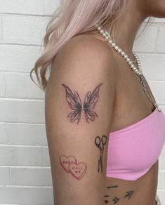 a woman with pink hair has a butterfly tattoo on her left shoulder and scissors in the other hand