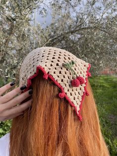 a woman with long red hair wearing a crocheted hat on top of her head