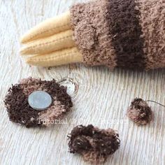 a stuffed animal is sitting on the floor next to some yarns and buttons that have been crocheted together