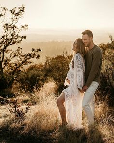 a man and woman standing on top of a hill