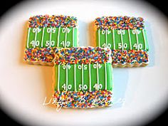 three decorated football field cookies sitting on top of a white plate covered in sprinkles