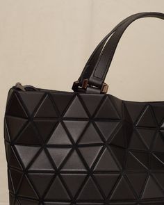 Easy large tote bag by Bao Bao Issey Miyake in black. Large carry-all tote with detachable shoulder strap in cowhide leather. Matte triangular tiles tessellate the exterior surface with a matte leather-like finish. Large internal capacity with secure pockets and nylon lining. Synthetic Leather, Polyester, Cowhide Leather.Made in Japan. Leather Triangle Shoulder Bag For Travel, Geometric Leather Shoulder Bag For Travel, Geometric Leather Travel Shoulder Bag, Leather Triangular Shoulder Bag For Travel, Triangle Shoulder Bag With Removable Pouch For Travel, Luxury Geometric Shoulder Bag For Everyday Use, Geometric Leather Travel Bag, Modern Triangular Shoulder Bag For Shopping, Black Geometric Bag For Everyday Use