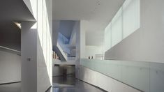 an empty hallway with white walls and flooring in the center is lit by sunlight coming through windows