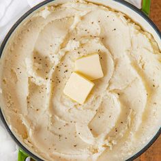 a pot filled with mashed potatoes and butter on top of a wooden table next to a white napkin