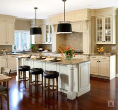 a large kitchen with an island in the middle and stools at the end,