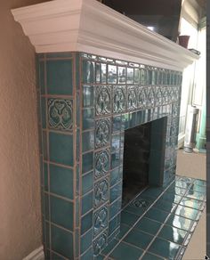 a fireplace with blue tiles and white trim