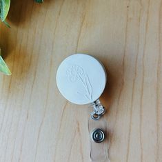 Have you been looking for the perfect badge reel to match with your work uniform? You're not alone -- Here's your solution.  The cutest, minimalistic badge reel you've ever seen! All handmade clay badge reels have a white background so they match with any outfit or uniform! Customizable by birth flower and optional initials or license! Great for a gift for a nurse, medical professional, SLP, and business professional. This listing is for one (1) swivel alligator clip retractable badge reel with Polymer Clay Name Badge, Clay Badge Reel, Leather Badge Reel, Customizable White Badge Reel For Gift, Affordable Black Retractable Badge Reel, Work Uniform, Jamais Vu, Clay Pieces, Work Uniforms