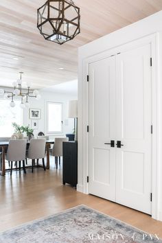 an open door leading to a dining room with chairs and a chandelier hanging from the ceiling