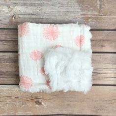 a white and pink blanket on top of a wooden floor next to a small stuffed animal