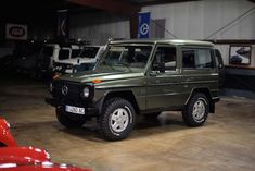 a green mercedes benz is parked in a garage