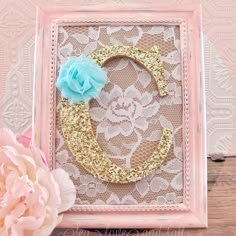 a pink and gold frame with a blue flower on the front, and a lace doily in the middle