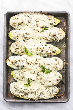 baked zucchini stuffed with cheese and herbs in a baking pan on a marble surface