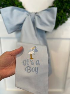 a person holding up a blue cloth with the words it's a boy on it