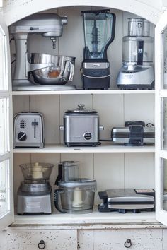 a kitchen shelf filled with appliances and blenders