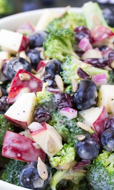 a salad with broccoli, blueberries and apples in it is ready to be eaten