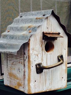 a bird house with a metal roof and door handle on the side of a window sill