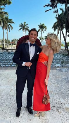 a man in a tuxedo standing next to a woman in a red dress