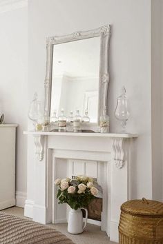 there is a vase with flowers in it next to a mirror on the fireplace mantel