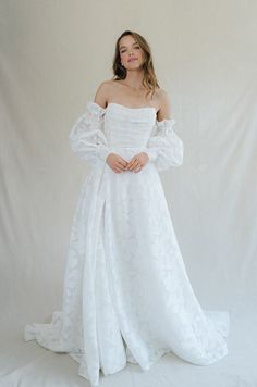 a woman in a white dress posing for the camera with her hands on her hips