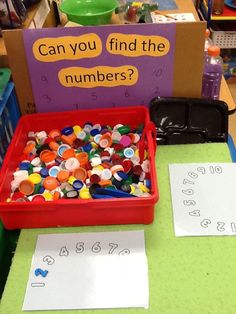 a red container filled with lots of colorful buttons next to a sign that says can you find the numbers?