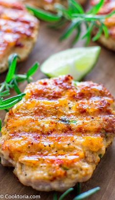 crab cakes with lemon wedges and rosemary on a cutting board, ready to be eaten