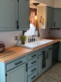 a kitchen with blue cabinets and wooden counter tops, along with a sink in the center