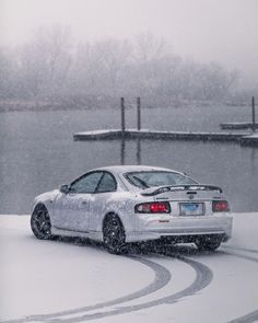 a white car driving down a snow covered road