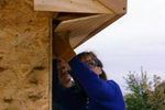 a woman is holding up a wooden structure