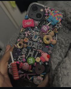 someone is holding their cell phone covered in candies and other things that are on it