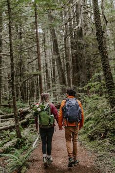 two people walking in the woods with backpacks