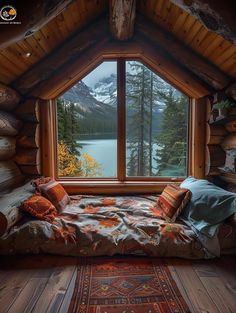 a bed sitting in front of a window next to a rug on top of a wooden floor