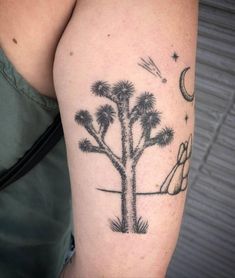 a woman's arm with a palm tree and moon tattoo on it