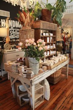 a flower shop with flowers and candles on the table in front of it's counter