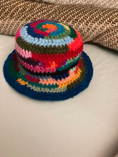 a multicolored hat sitting on top of a bed next to a throw pillow