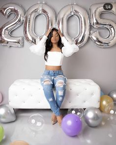 a woman sitting on top of a couch in front of balloons and letters that spell 205