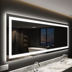 a bathroom with two sinks and a large mirror over it's counter top that is illuminated by lights