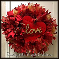 a heart shaped wreath with the word love painted on it's side and red ribbon