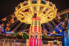 a carnival ride at night with lights on it's sides and merry go round in the background