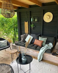 an outdoor seating area with cushions and pillows on the back porch, surrounded by greenery