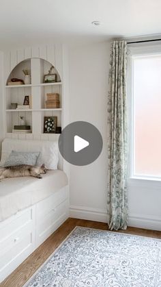 a cat laying on top of a bed next to a window in a room with white walls