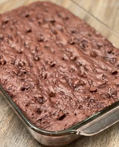 a chocolate cake in a glass dish on a wooden table