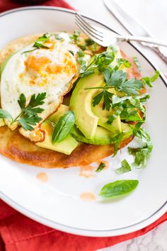 an egg and avocado sandwich is on a plate with a fork, knife and napkin