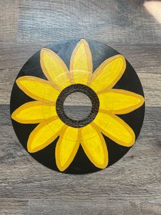 a painted sunflower on a black and yellow plate sitting on a wooden table top