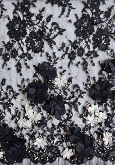 black and white lace with flowers on the bottom is shown in close up, as well as beads