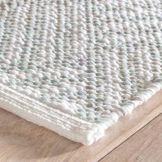 a close up view of a rug on a wooden floor with white and blue colors