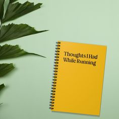 a yellow notebook sitting on top of a green table next to a leafy plant