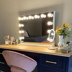 a desk with a chair, mirror and lights on it