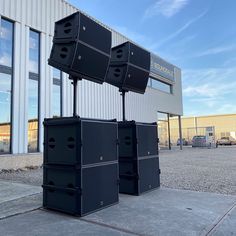 four black boxes are stacked on top of each other in front of a building