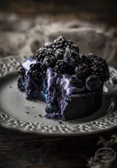 a piece of blueberry cheesecake on a white plate with some blackberries around it