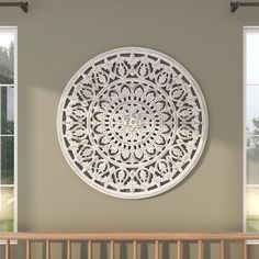 a large white circular cutout hanging on the side of a wall next to two windows